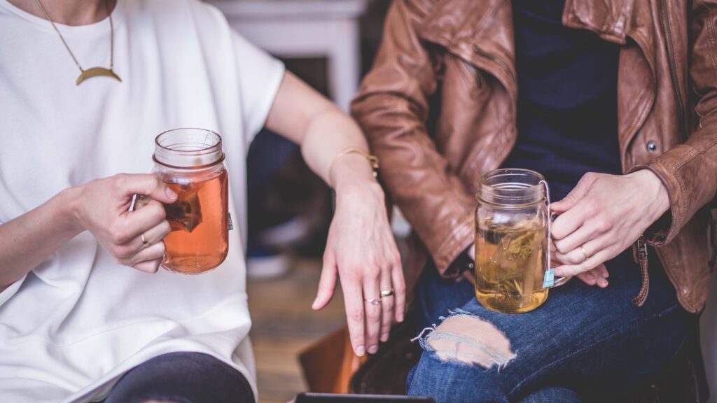 two people sitting while holding mugs of tea