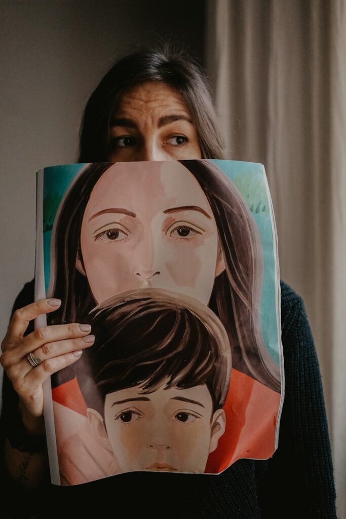woman in black knit sweater covering her face with a painted self portrait.