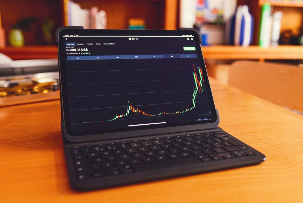 A laptop showing a financial graph. The line is going upwards over time.